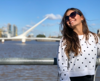 Uma mulher feliz apoiada no corrimão de uma ponte em frente ao um lago