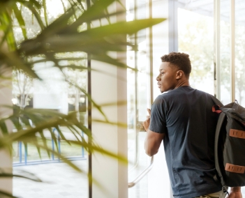 Uma rapaz atravessando a porta para sair do campus universitário